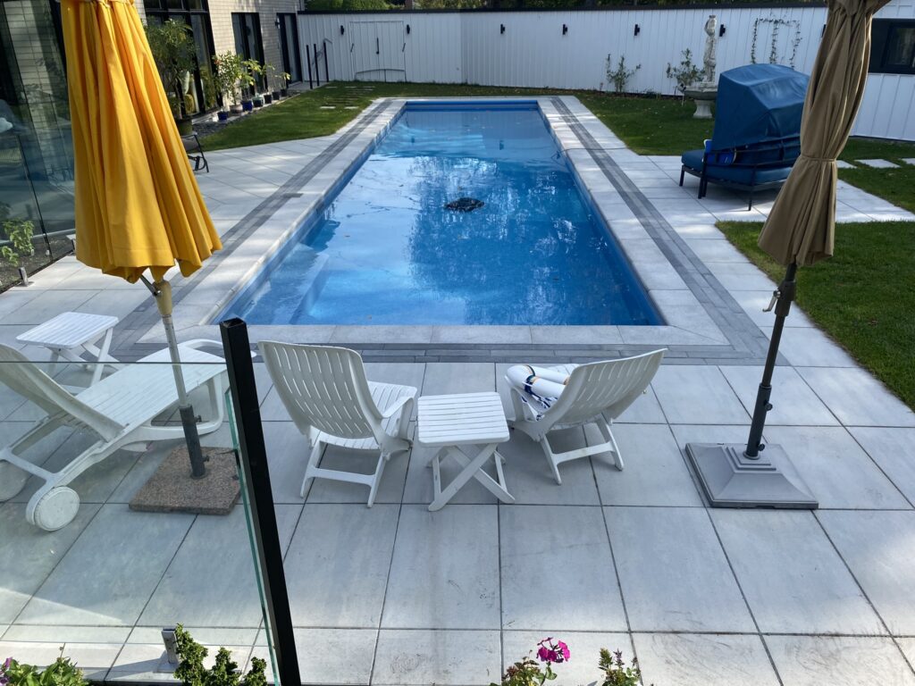 Bordure de piscine et patio en pierre avec parasols et chaises de parterre